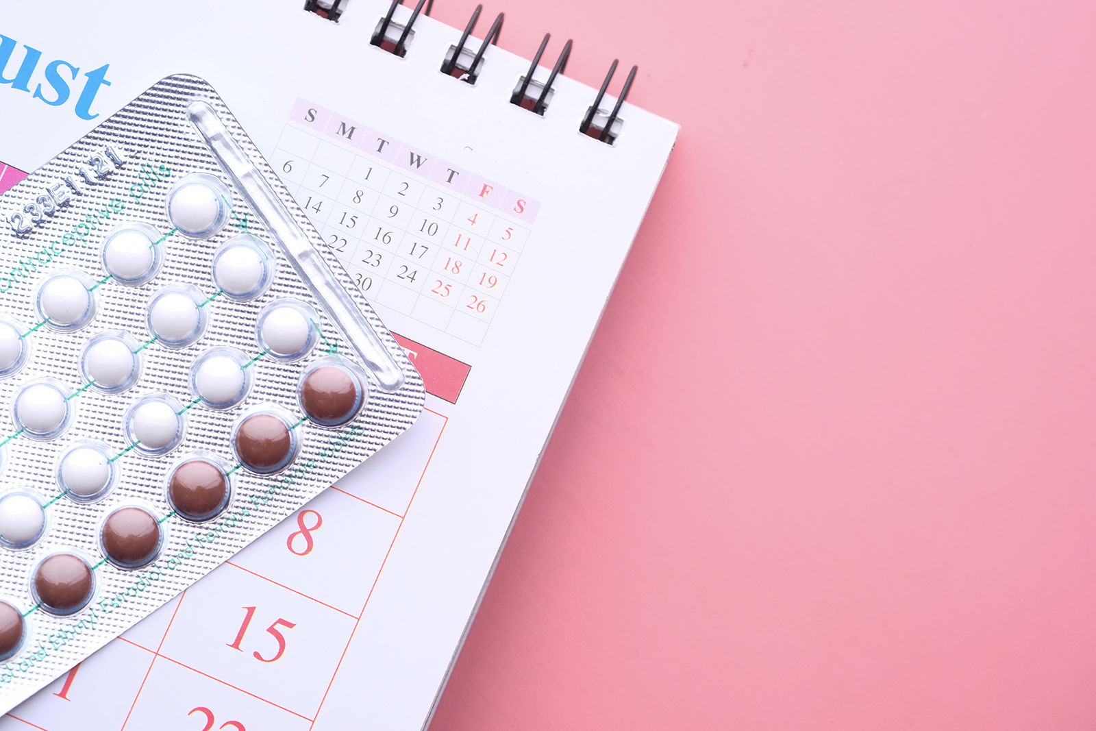 birth control pills , calendar and notepad on table